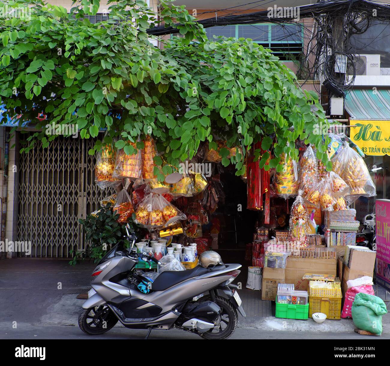 Vietnamita acquistare carta votiva come offerte di culto, tradizionale culturale di stile di vita vietnamita, negozio sotto albero con ramo di albero sul tetto il giorno Foto Stock