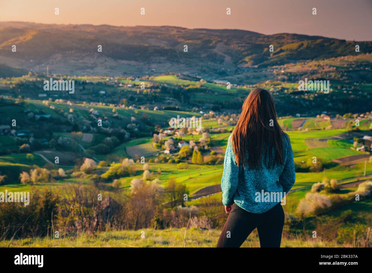 Donna che guarda la natura mattina di primavera. Luce calda alba e alberi in fiore sullo sfondo. Modifica lo spazio per il preventivo o il montaggio Foto Stock