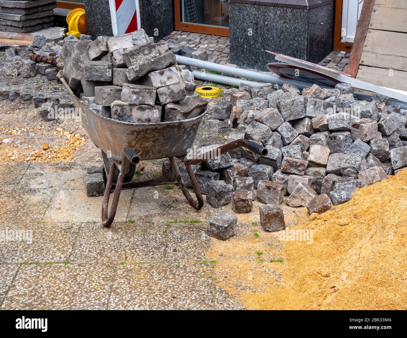 Carriola con pavimentazione in pietra costruzione stradale Foto Stock