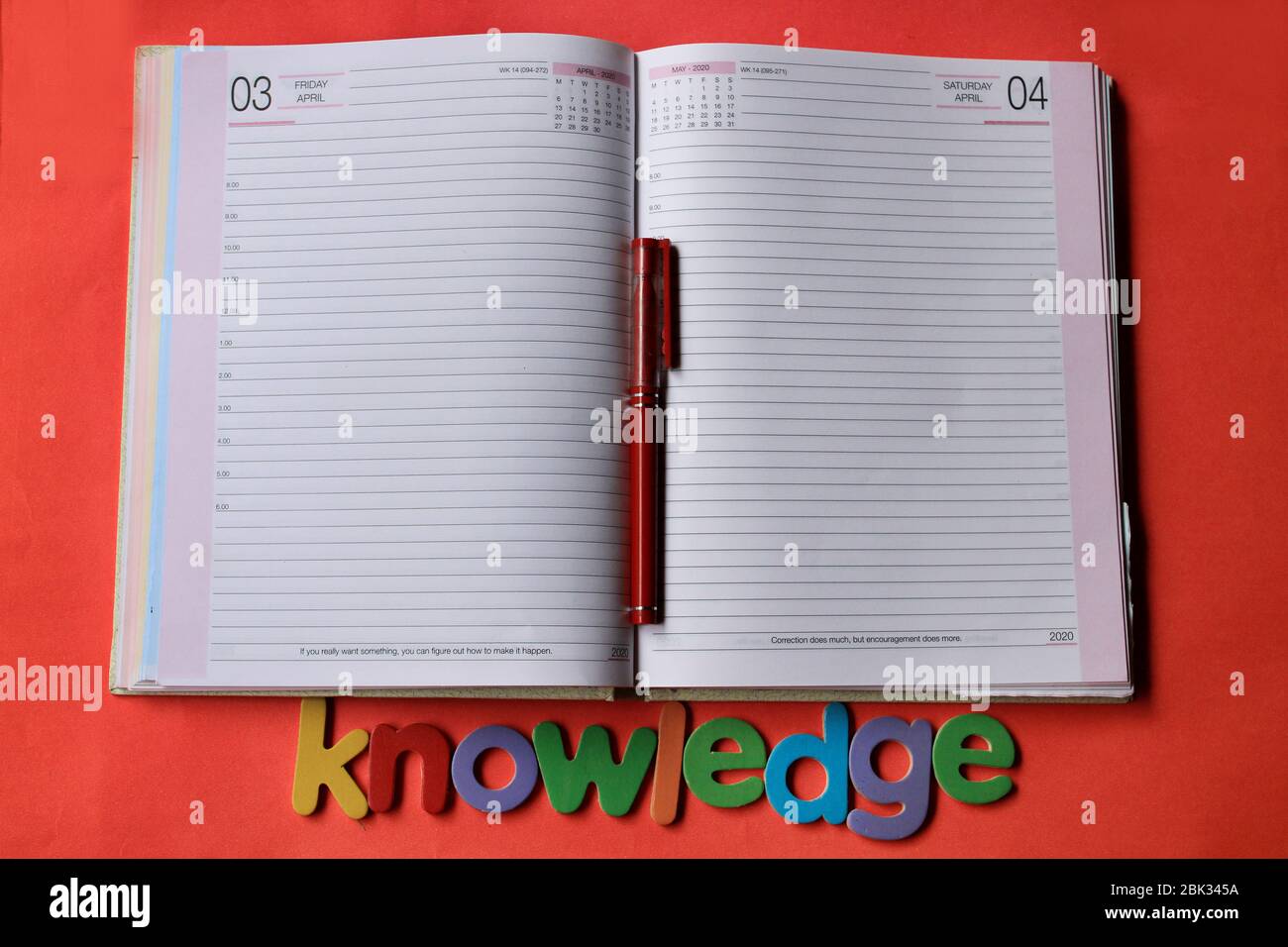 La parola conoscenza scritta su sfondo rosso con Diario pagina e penna. Foto Stock
