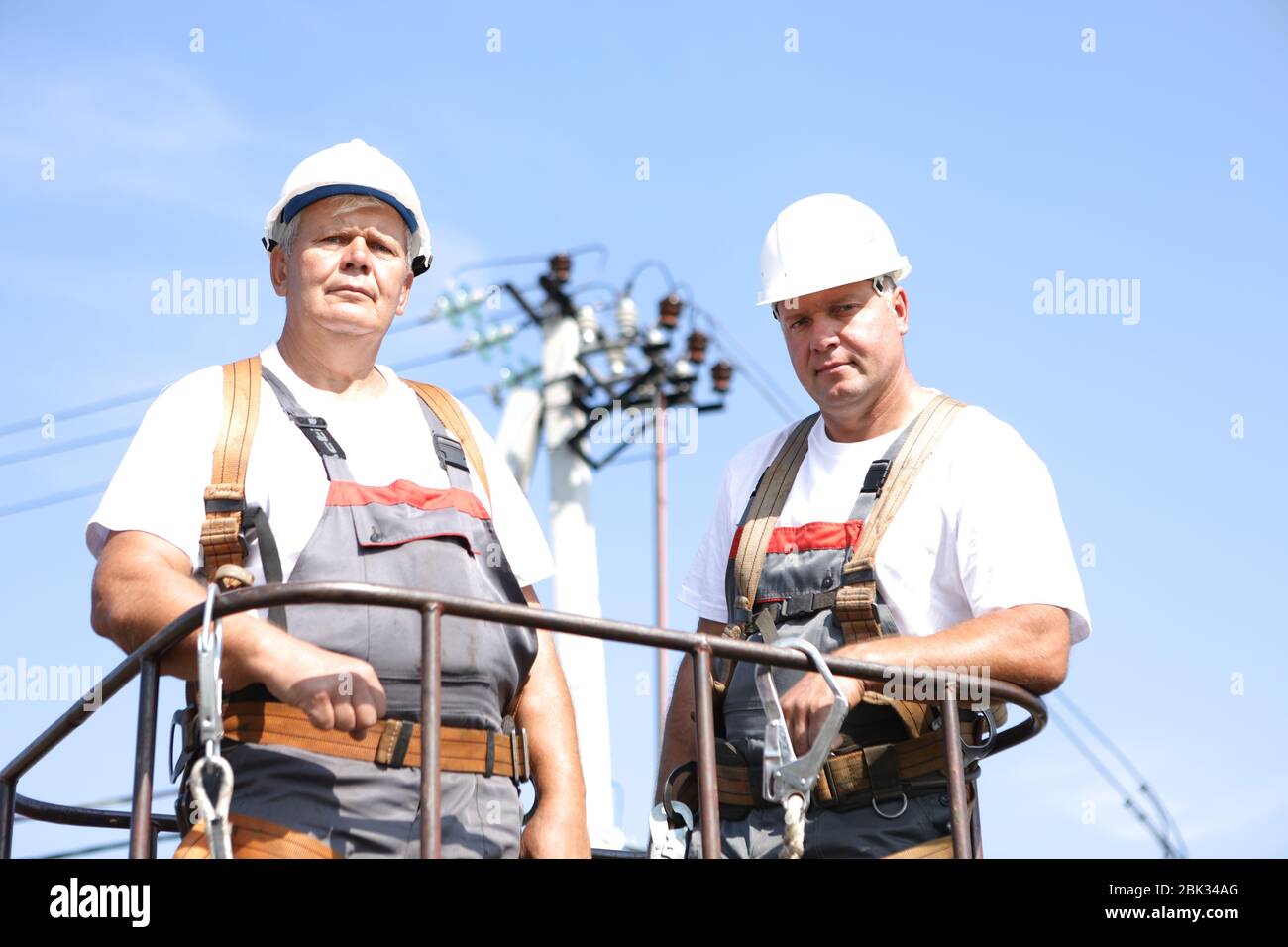 Due lavoratori elettrici su un ascensore. Gli ingegneri si alzano su una gru per riparare un supporto alto. Gli uomini eliminano l'incidente alla stazione di alta quota Foto Stock