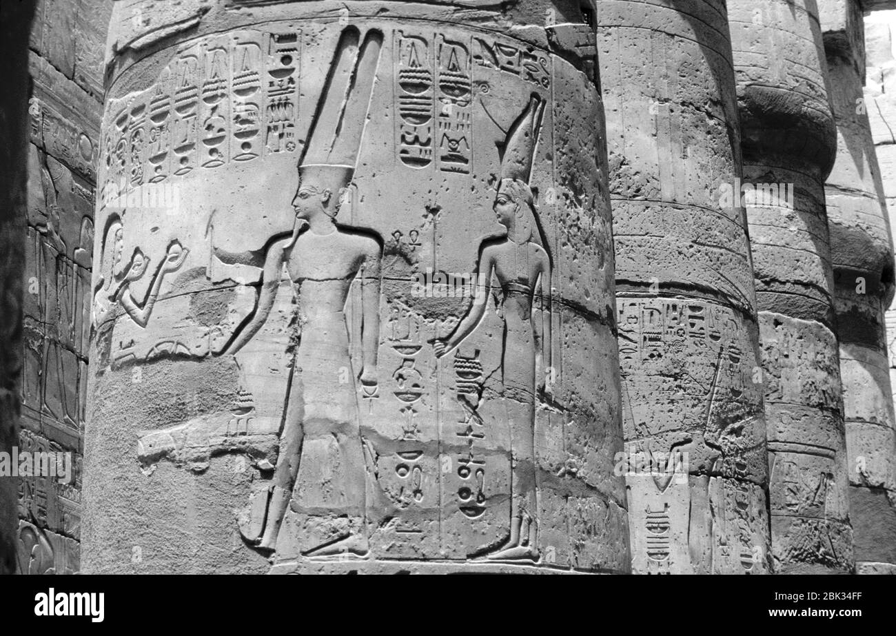 I turisti visitano le colonne del Tempio di Karnak nella città monumentale di Tebe vicino a Luxor, Egitto. I geroglifici egiziani decorano le pareti della t. Foto Stock