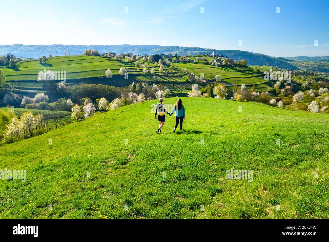 Coppia data in verde primavera fioritura paesaggio soleggiato. Paesaggio rurale e chiesa in background Foto Stock