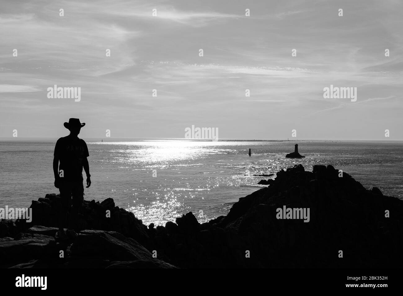 Un uomo solitario in un cappello si trova alla fine della Pointe du Raz in Bretagna, Francia e si affaccia sull'oceano Foto Stock