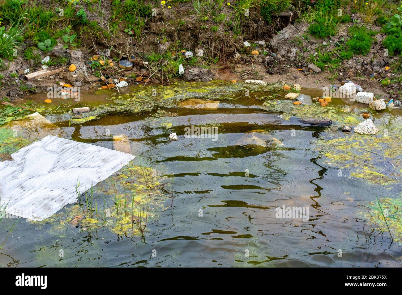 Una pudle sporca inquinata da vari rifiuti e rifiuti a causa della presenza dell'industria. Inquinamento dell'acqua. I rifiuti inquinano le nostre acque. Foto Stock