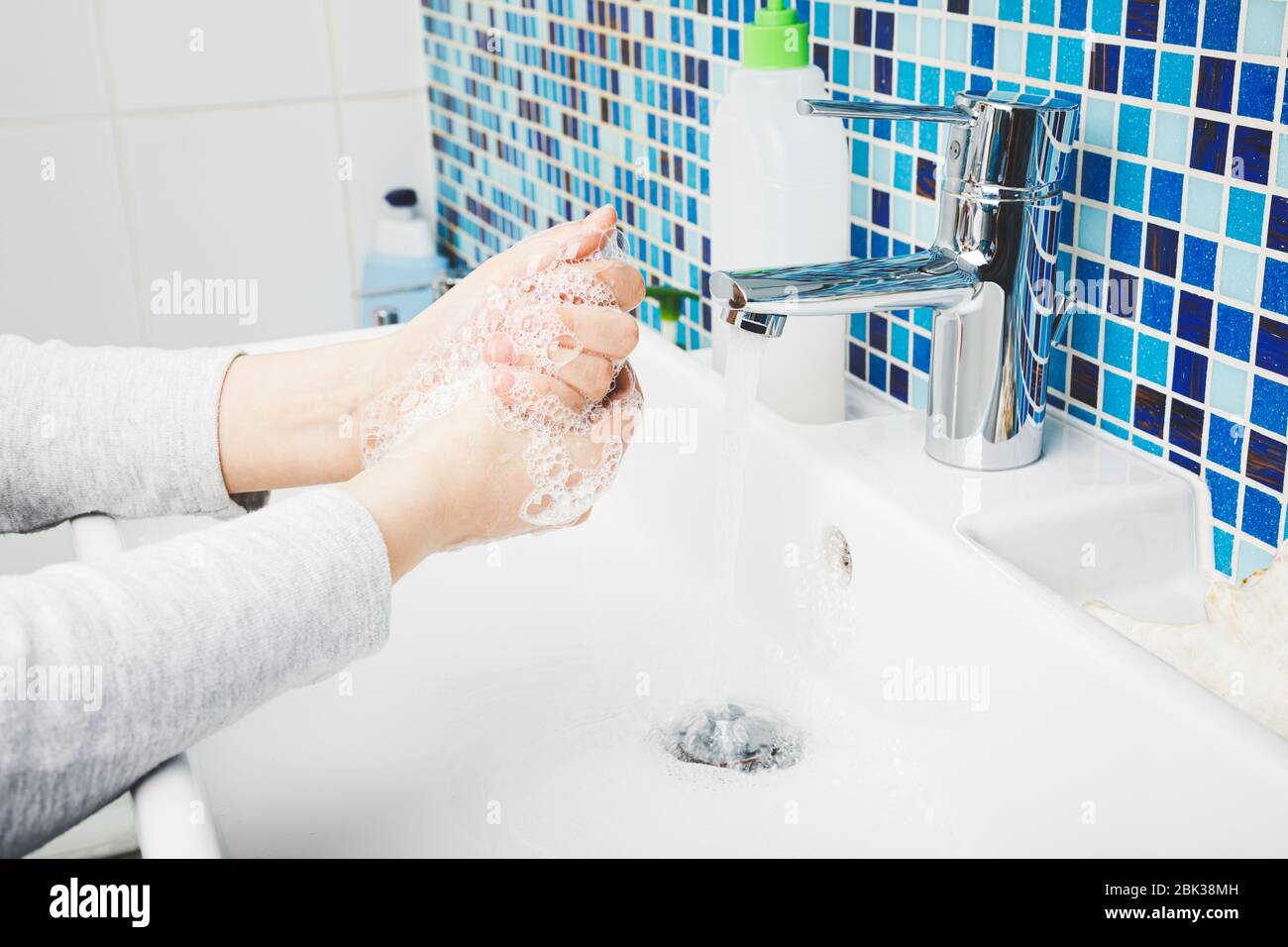 Il bambino lava diligentemente le mani con sapone antibatterico e acqua eseguendo le misure protettive di base contro la diffusione di deseas COVID-19 di coronavirus Foto Stock