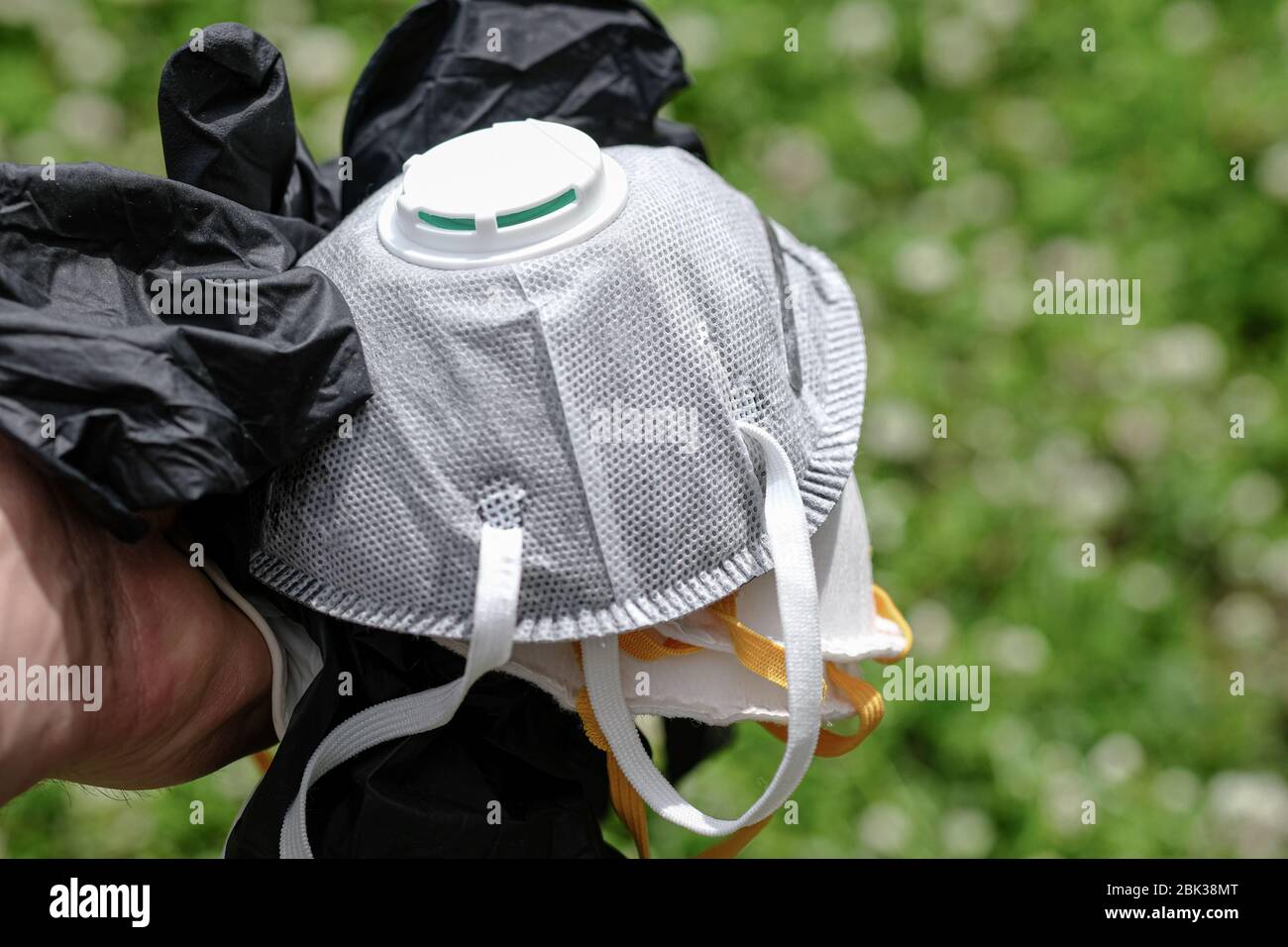 Uomo tenere maschera protettiva ffp2 e guanti rifiuti rifiuti rifiuti rifiuti di erba Ground.covid coronavirus malattia inquinamento da rifiuti Foto Stock