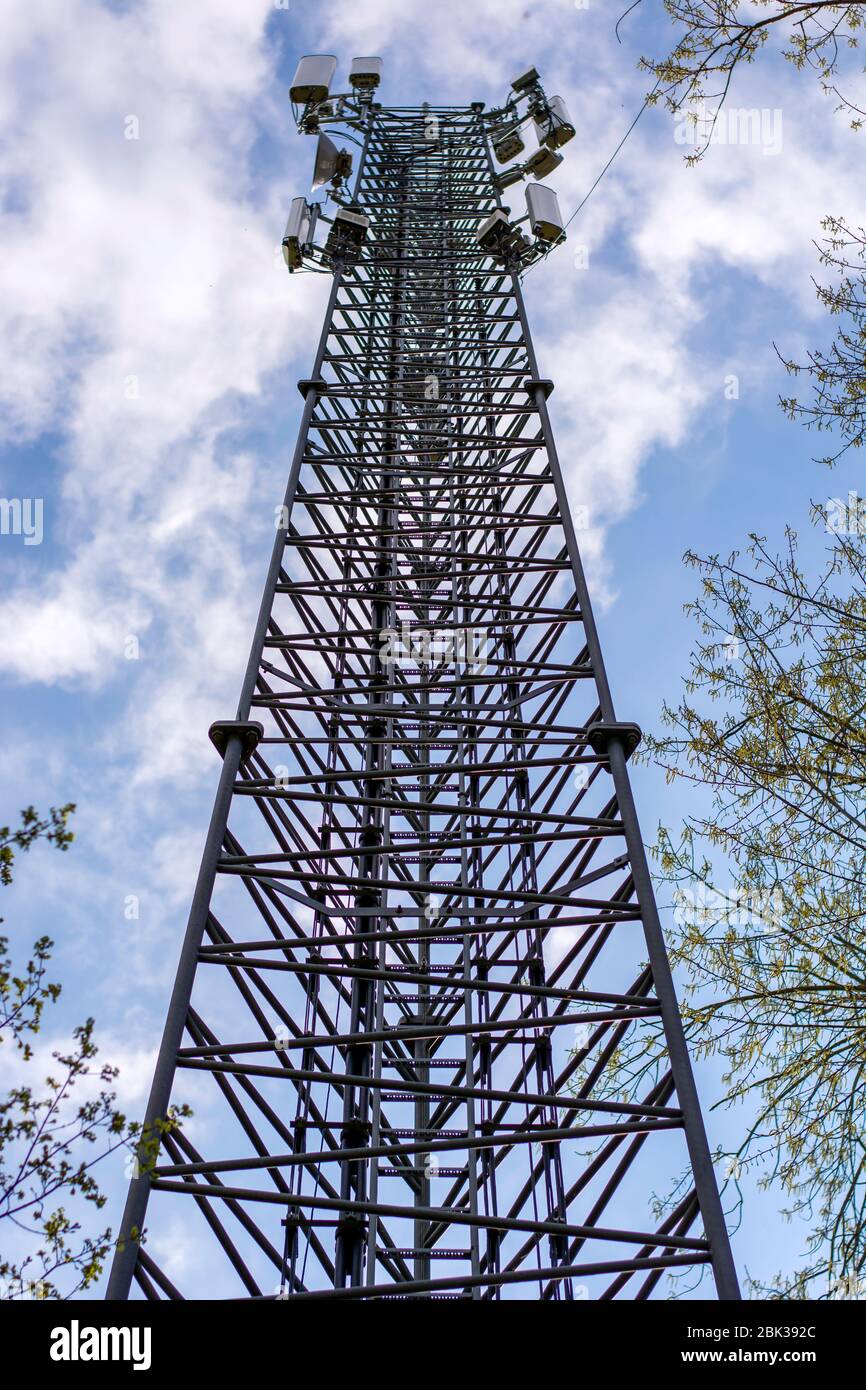 Torre di telecomunicazione della rete mobile della stazione base di antenna della rete cellulare 4G e 5G tra alberi. Trasmettitore antenna di comunicazione wireless ma Foto Stock