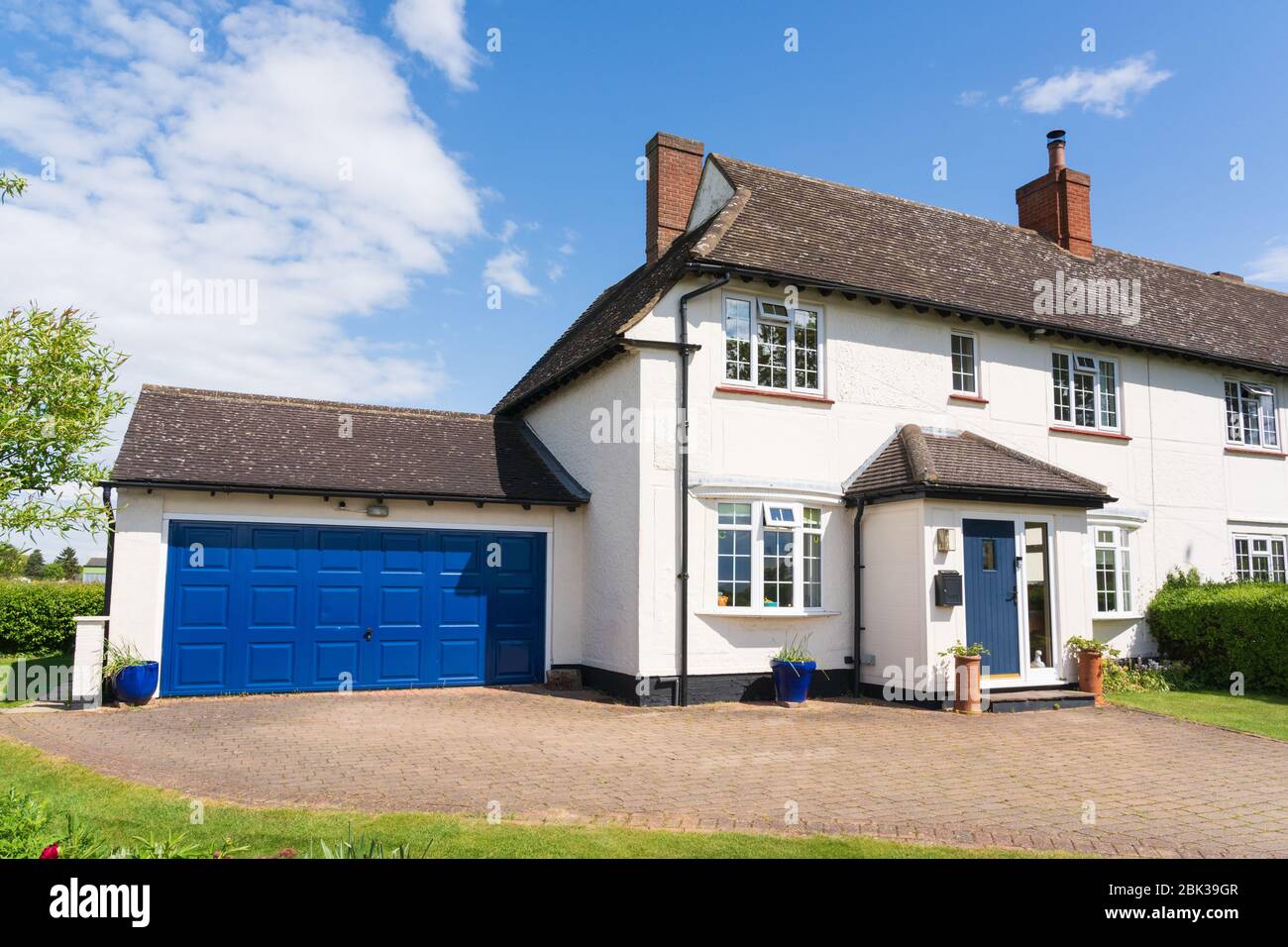 Esterno di un ex 1920 semi-indipendente consiglio casa con aggiunto portico, doppio garage e vialetto. Disponibile anche la versione con auto in strada. Foto Stock