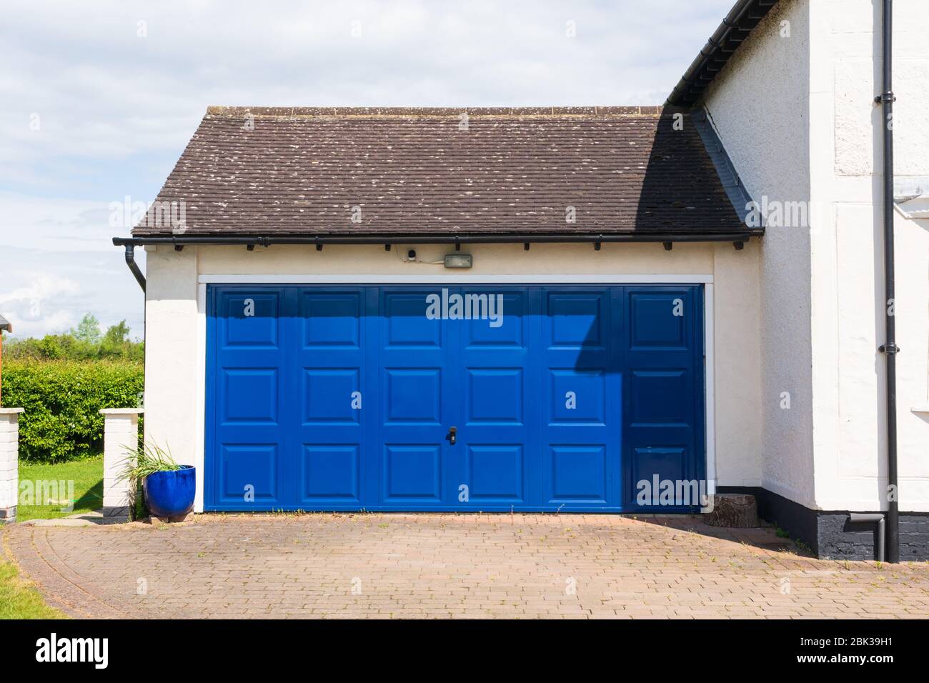 Esterno di un doppio garage con un metallo blu su e sopra porta attaccato ad una casa. Hertfordshire. REGNO UNITO Foto Stock