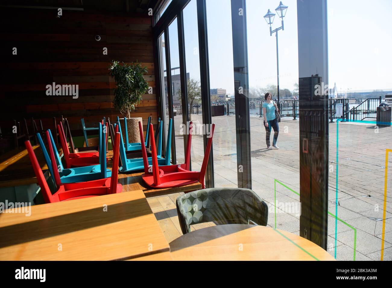10.04.20 - UN escursionista gode il sole nella baia di Cardiff mentre passa il ristorante Las Iguanas che è chiuso Foto Stock