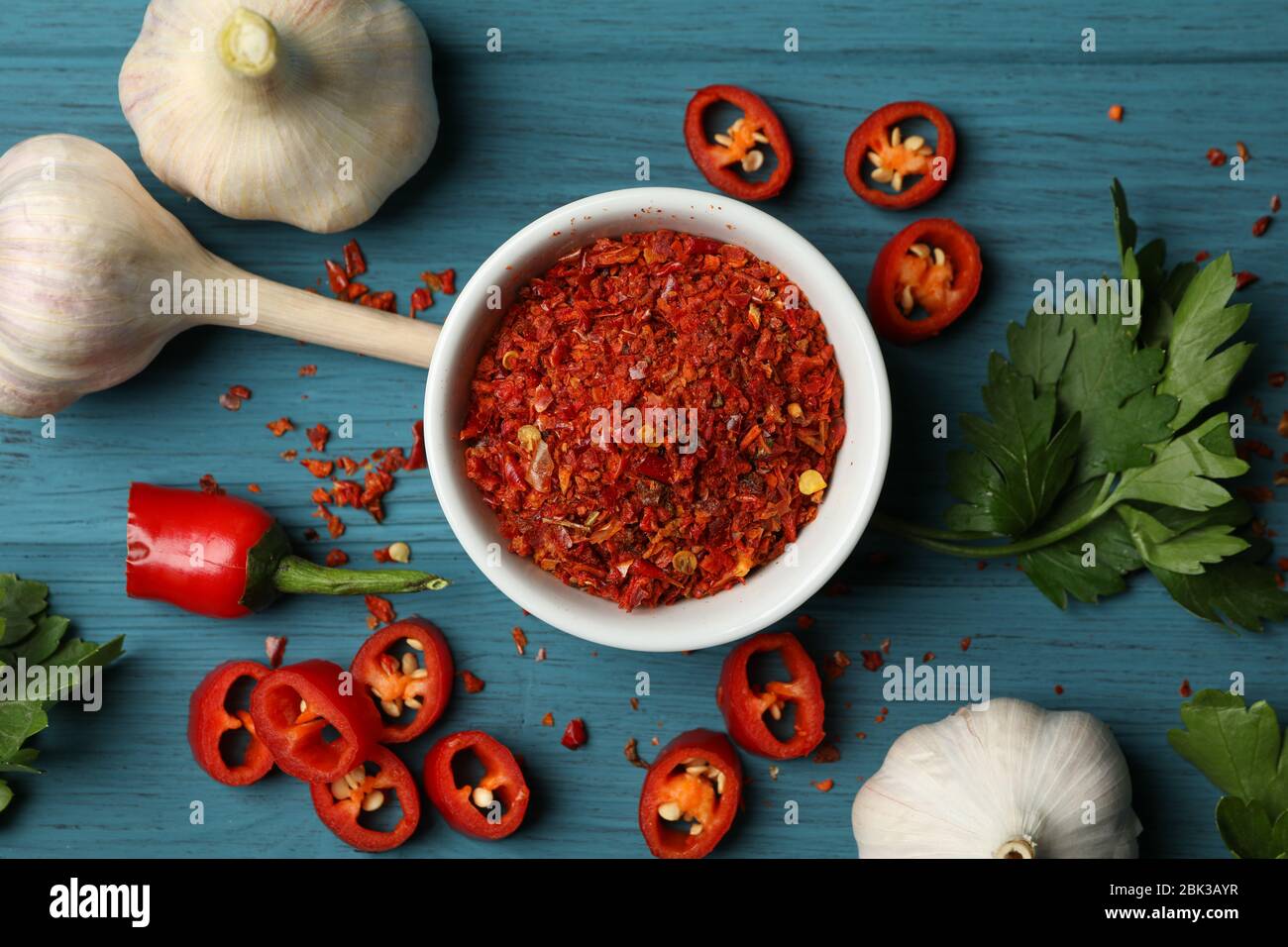 Ciotola con spezie a polvere calda e ingredienti su sfondo di legno Foto Stock