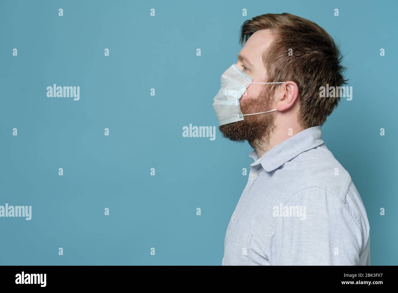 Uomo con barba aglita per il quale la maschera medica non si adatta bene e non crea la protezione completa. Spazio di copia. Foto Stock