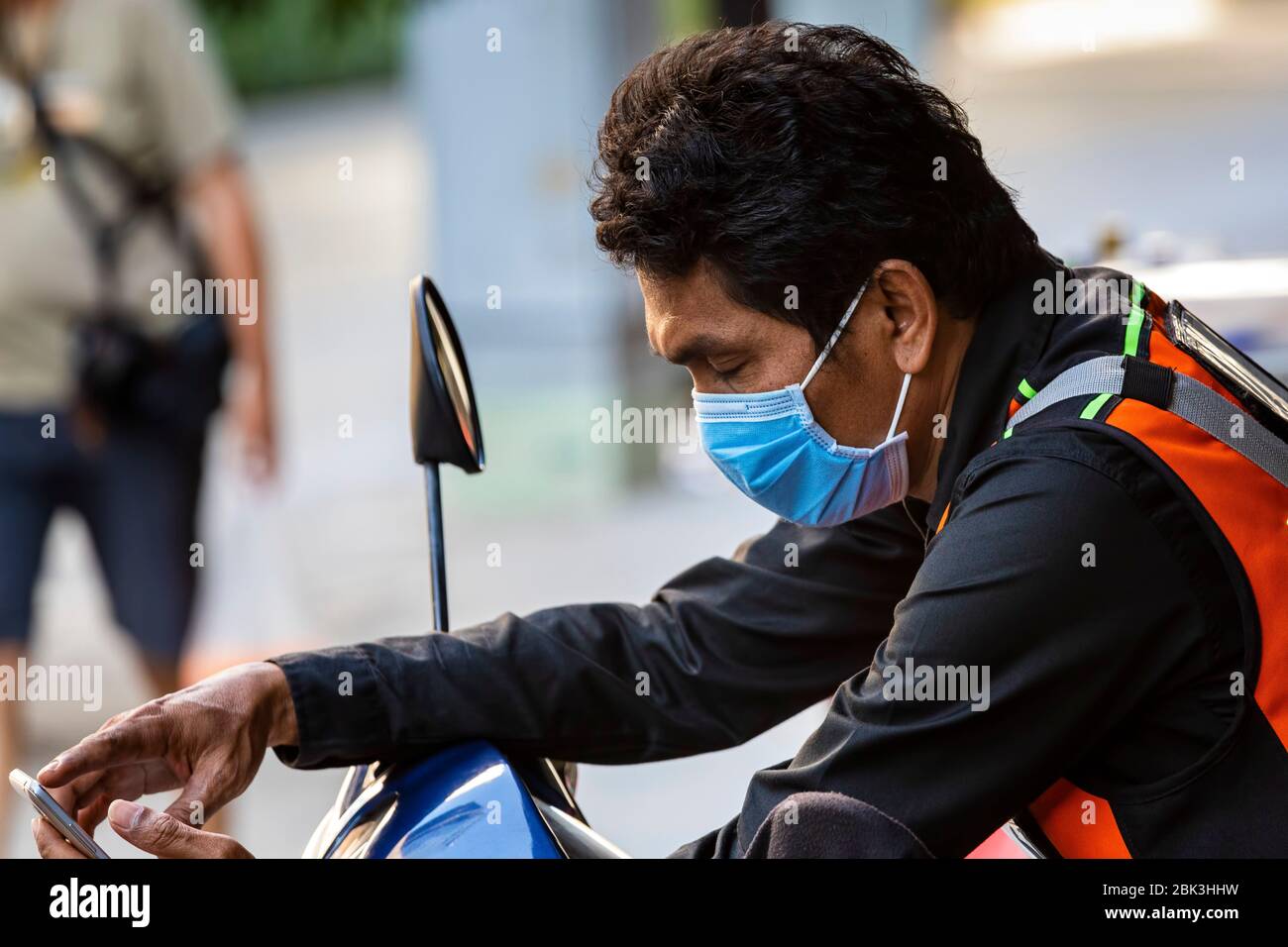 Tassista thailandese con maschera e telefono cellulare durante la pandemia Covid 19, Bangkok, Thailandia Foto Stock
