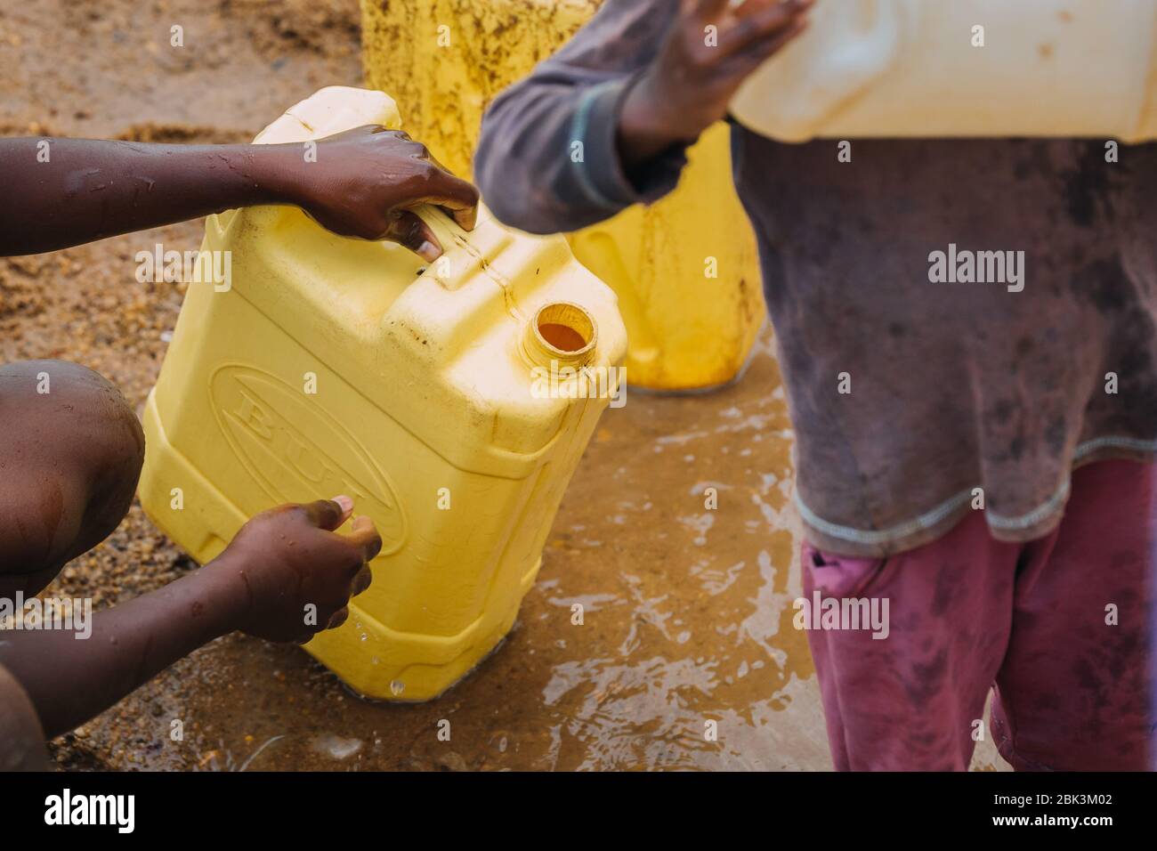 Persone che ottengono acqua in un pozzo con lattine d'acqua Foto Stock