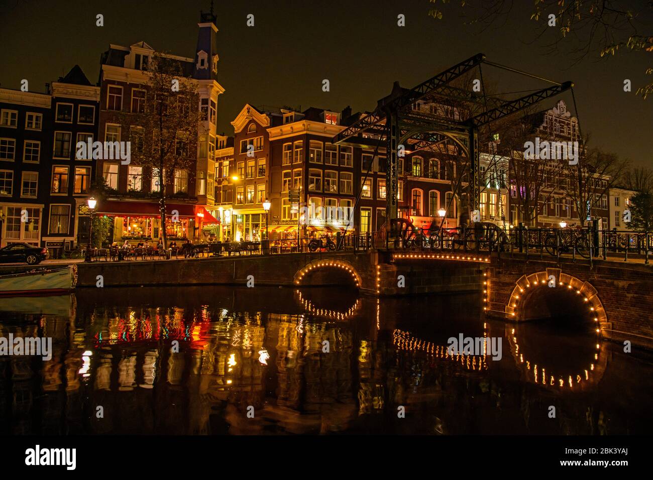 Riflessioni di luci a ponte nei canali al tramonto, Amsterdam, Olanda del Nord, Olanda Foto Stock
