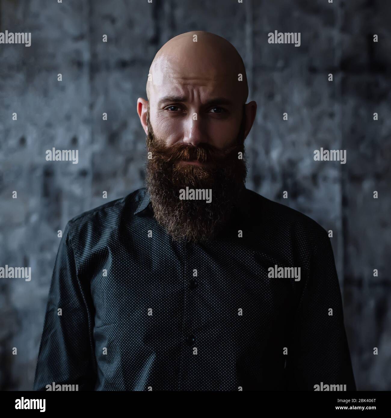 Ritratto di un bell'uomo bearded audace di mezza età in camicia nera su sfondo scuro Foto Stock