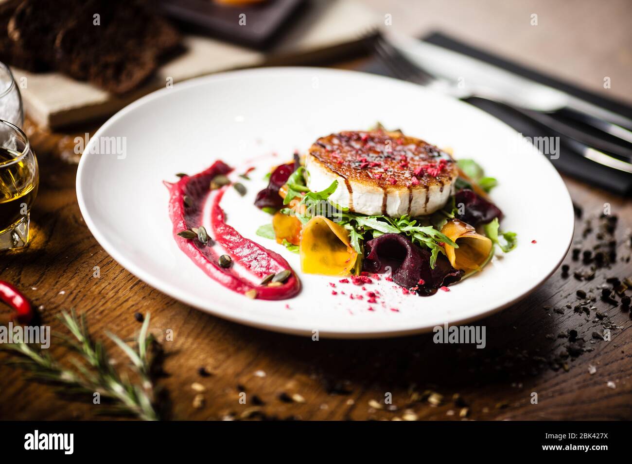 Insalata di formaggio di capra alla griglia: Barbabietola e zucca sottaceto, marmellata di mirtilli rossi, semi di zucca su un piatto bianco. Delizioso sano mediterraneo tradizionale Foto Stock