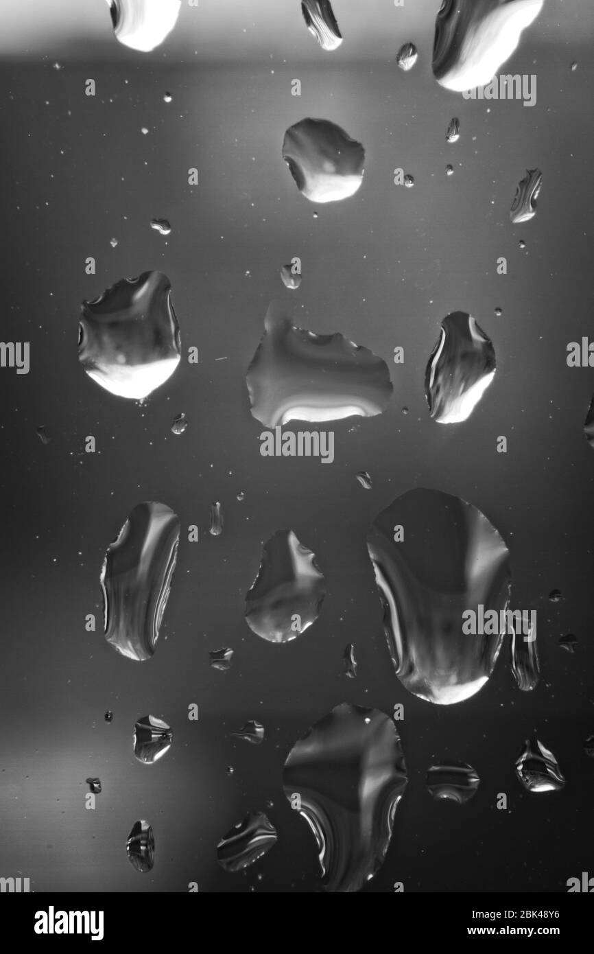 Immagine macro monocromatica di raindrop in primo piano su un riquadro di vetro trasparente. Foto Stock
