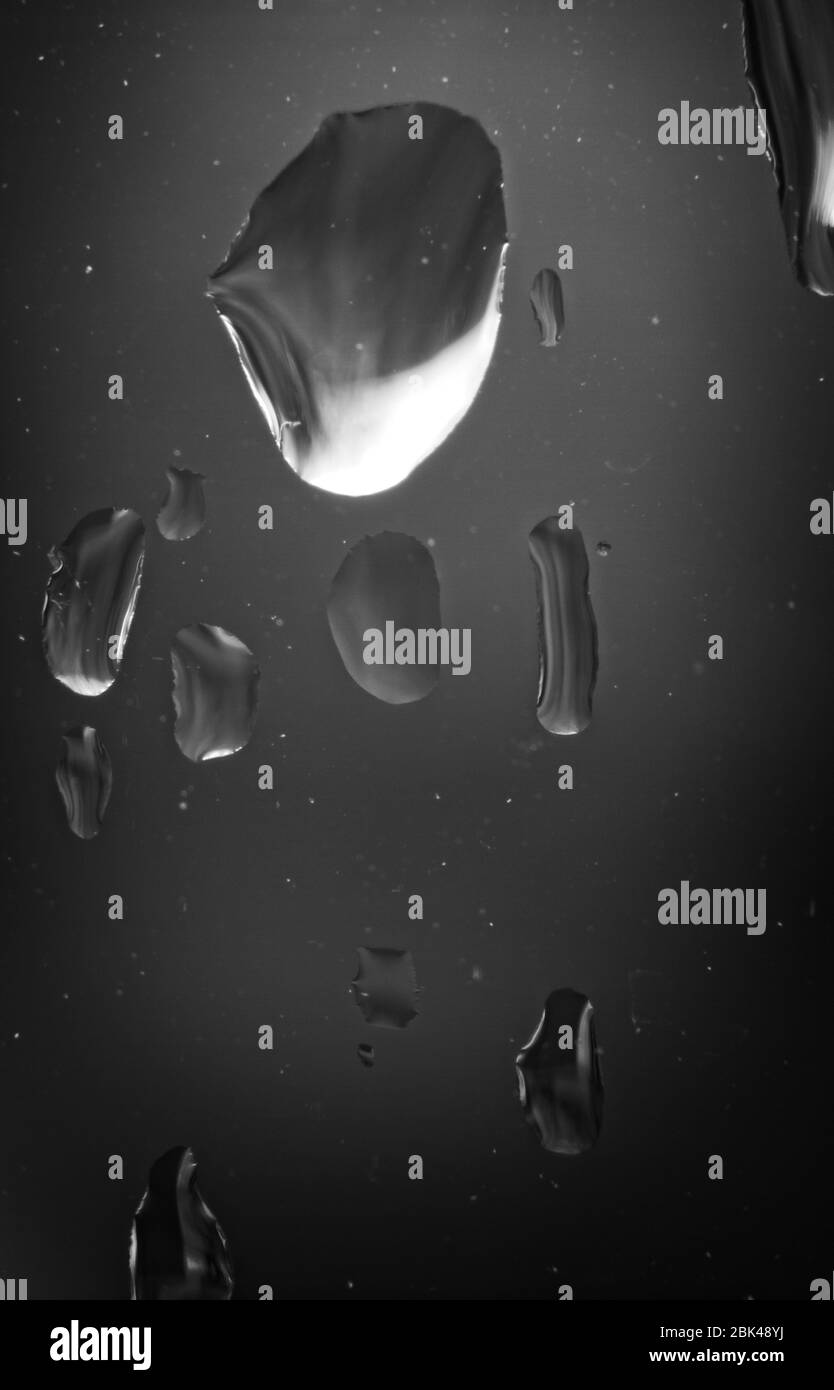 Immagine macro monocromatica di raindrop in primo piano su un riquadro di vetro trasparente. Foto Stock