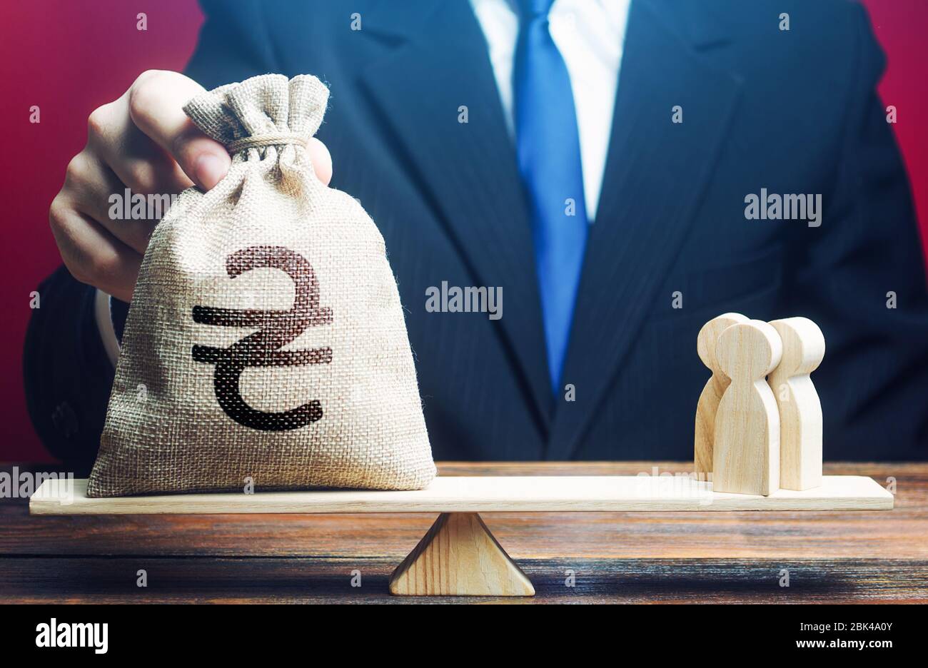 L'uomo mette il sacchetto ucraino di soldi di hryvnia su scale con una famiglia. Aiutare gli immigrati. Compensazione e sostegno finanziario per contribuire agli effetti del quaran Foto Stock