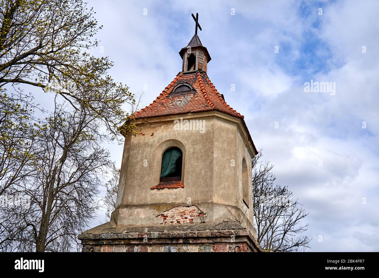 Vecchia torre con una croce vicino alla chiesa in campagna Foto Stock