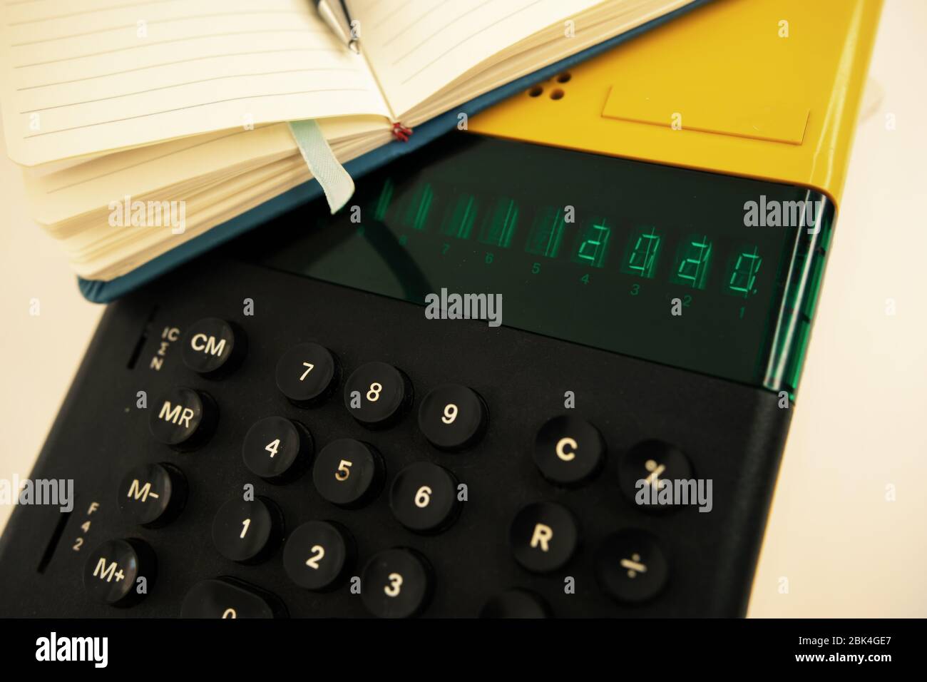 Vecchio modello di computer degli anni '80 su sfondo bianco, è acceso scrive 2020 e un notebook con una penna pronta per le note. Foto Stock