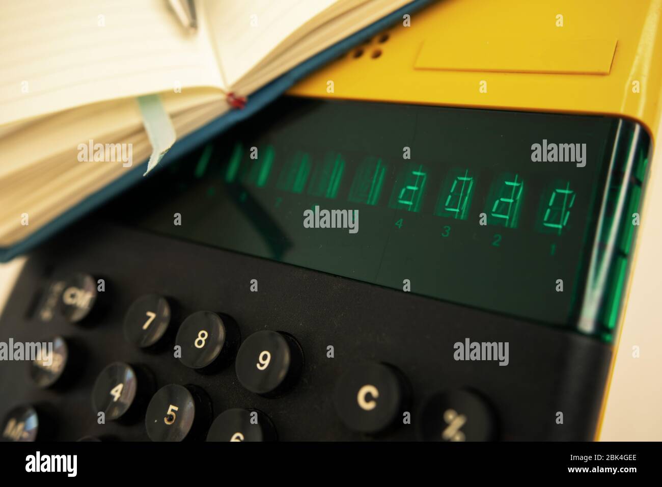 Vecchio modello di computer degli anni '80 su sfondo bianco, è acceso scrive 2020 e un notebook con una penna pronta per le note. Foto Stock