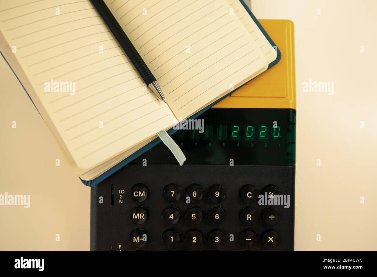 Vecchio modello di computer degli anni '80 su sfondo bianco, è acceso scrive 2020 e un notebook con una penna pronta per le note. Foto Stock