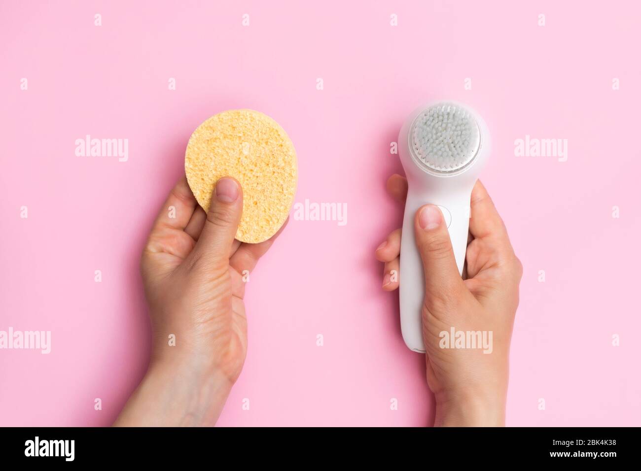 Spazzola per il viso o spugne per il viso concetto di scelta. Sfondo rosa pastello, vista dall'alto Foto Stock