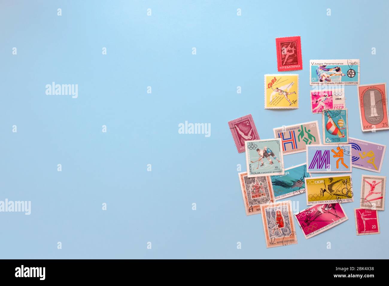 Una collezione di vecchi e costosi francobolli rari legati a sport e giochi olimpici di diversi paesi su sfondo blu. Vista dall'alto. Spazio di copia Foto Stock