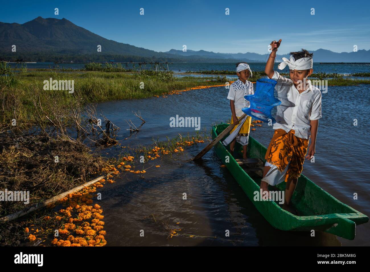 Lago Batur, Kintamani, Bangli, Bali, Indonesia - 28 giugno 2019 : cercando di catturare un pesce di due ragazzi balinesi in abiti tradizionali sul lago Batur Foto Stock