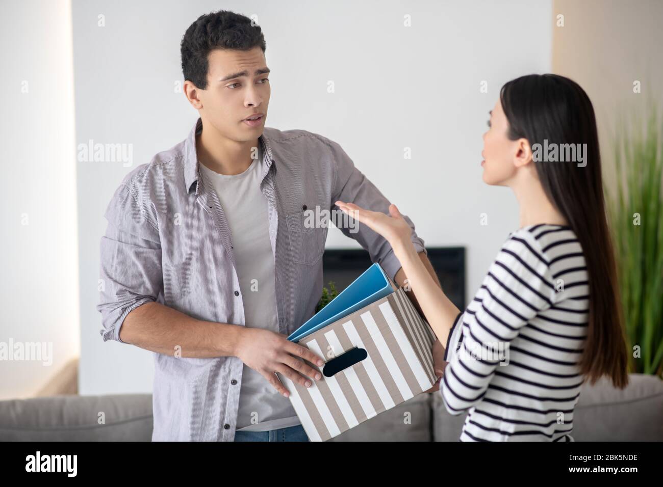 Giovane marito e moglie in piedi di fronte a discutere. Foto Stock
