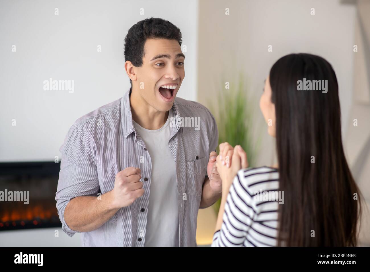 Giovane uomo che gioisce davanti alla moglie. Foto Stock