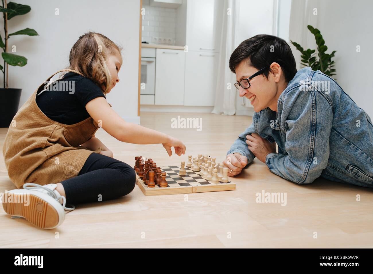 Padre e bambina che giocano a scacchi su un piano cucina a casa Foto Stock