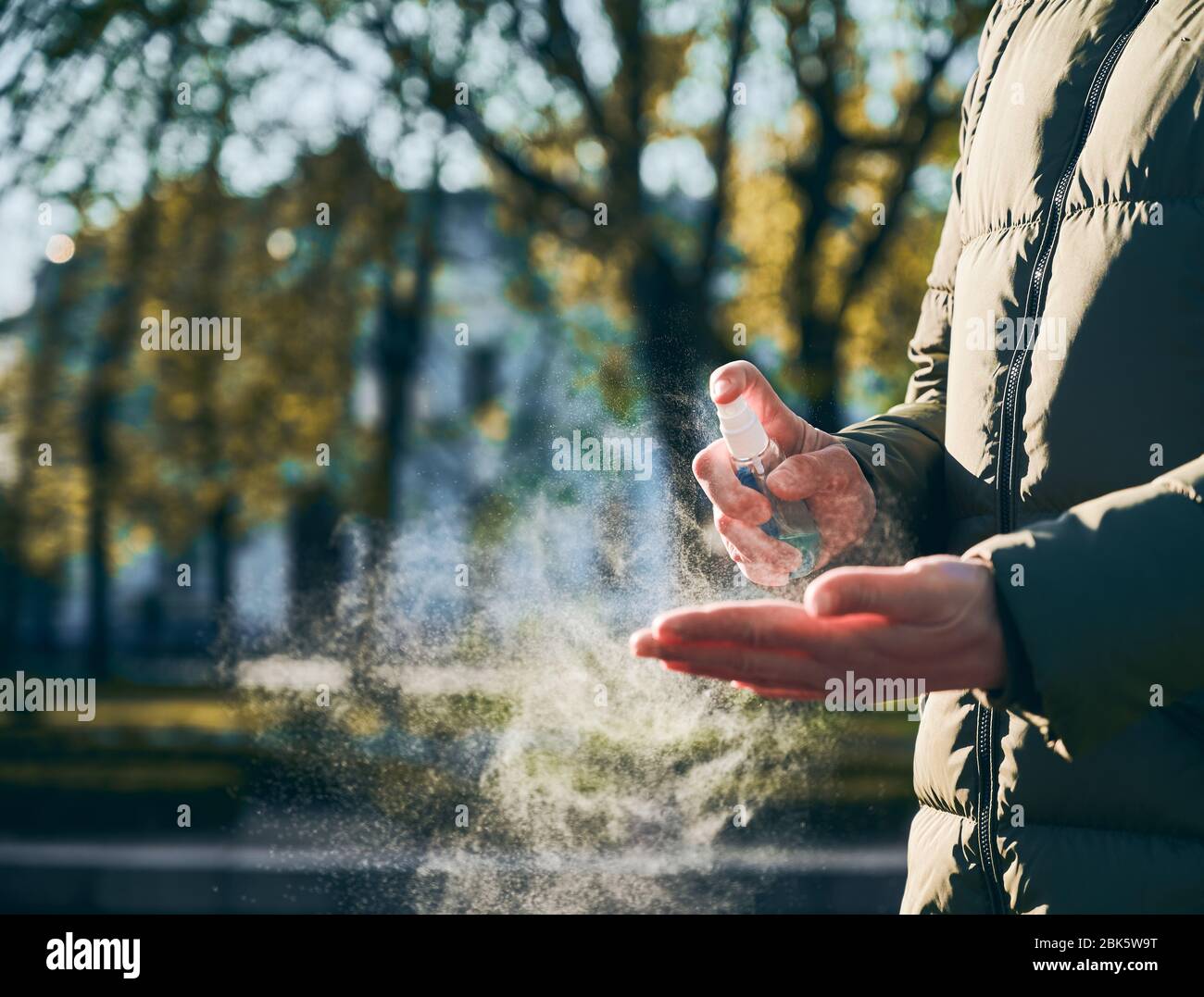 Snapshot ritagliato primo piano delle mani della donna che le strofinano le mani con spray a base di alcol, il giorno di primavera soleggiato, come misura di igiene preventiva contro l'infezione da coronavirus. Quarantena di Covid-19 2020 Foto Stock