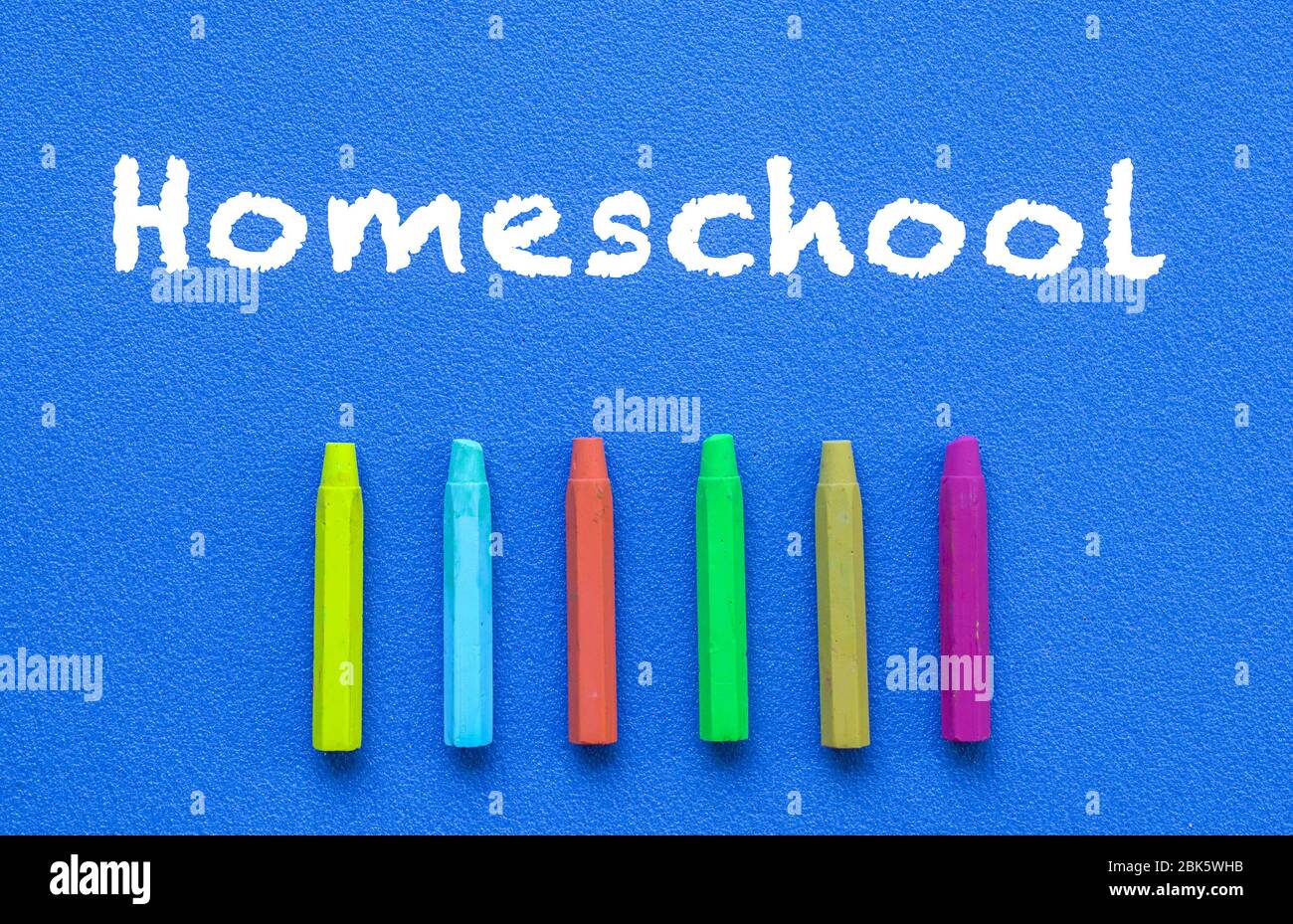 Homeschool. Parole o testo digitato su lavagna blu. Pastelli colorati. Vista dall'alto. Concetto di istruzione. Foto Stock