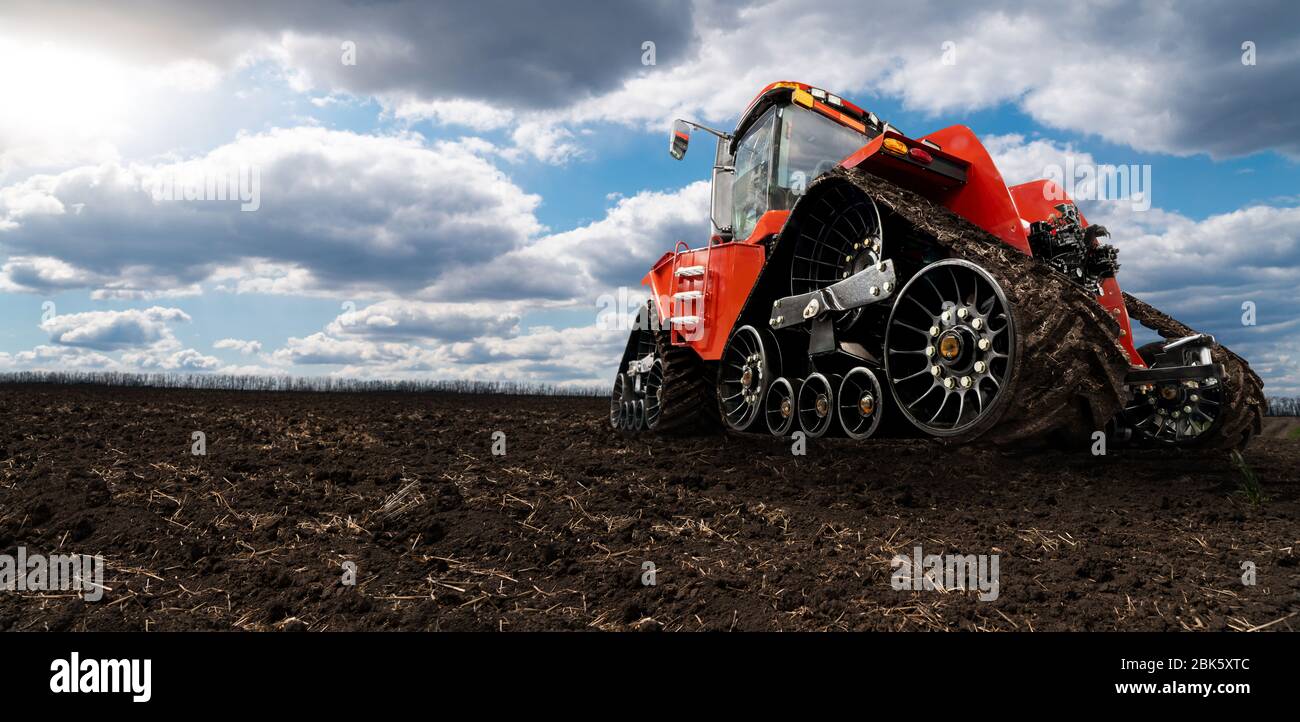 Trattore agricolo cingolato in gomma su un campo. Foto Stock