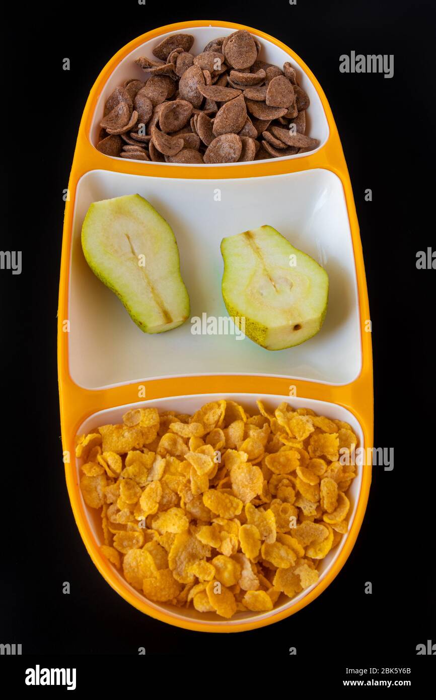Cereali in vassoio con latte e fette di pera isolati su sfondo grigio nero, una deliziosa e sana colazione dietetica. Vista dall'alto Foto Stock