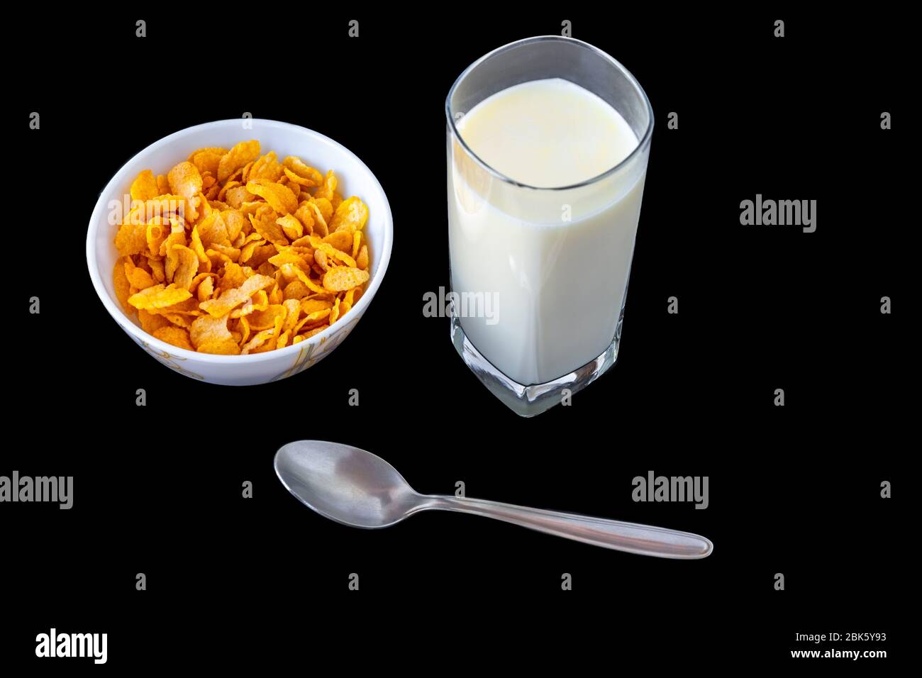 Cereali in fiocchi di mais in ciotola con latte isolato su sfondo grigio nero, una deliziosa e sana colazione dietetica. Foto Stock