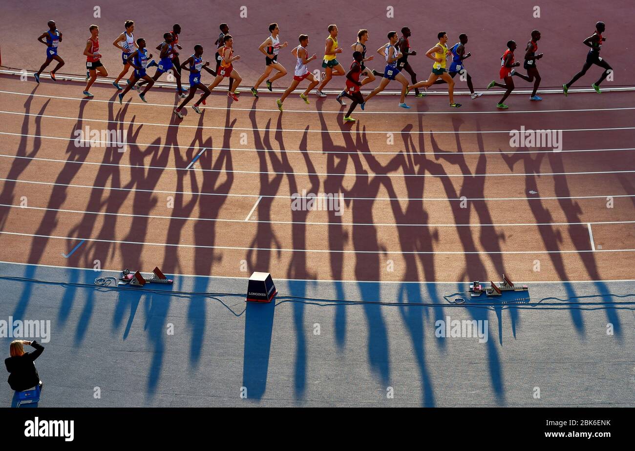 Giochi del Commonwealth di Glasgow 2014. Atletica, Hampden Park. Uomini 10.000 m finale. I corridori gettano lunghe ombre durante la gara. Foto Stock