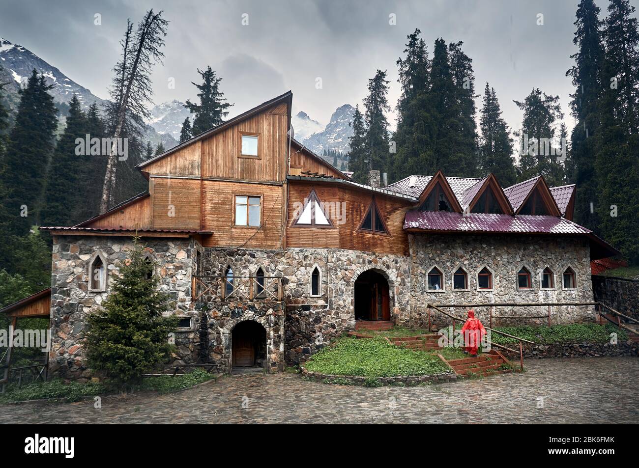 Donna della pioggia rossa manto di copertura in prossimità del vecchio castello nella valle di montagna Foto Stock