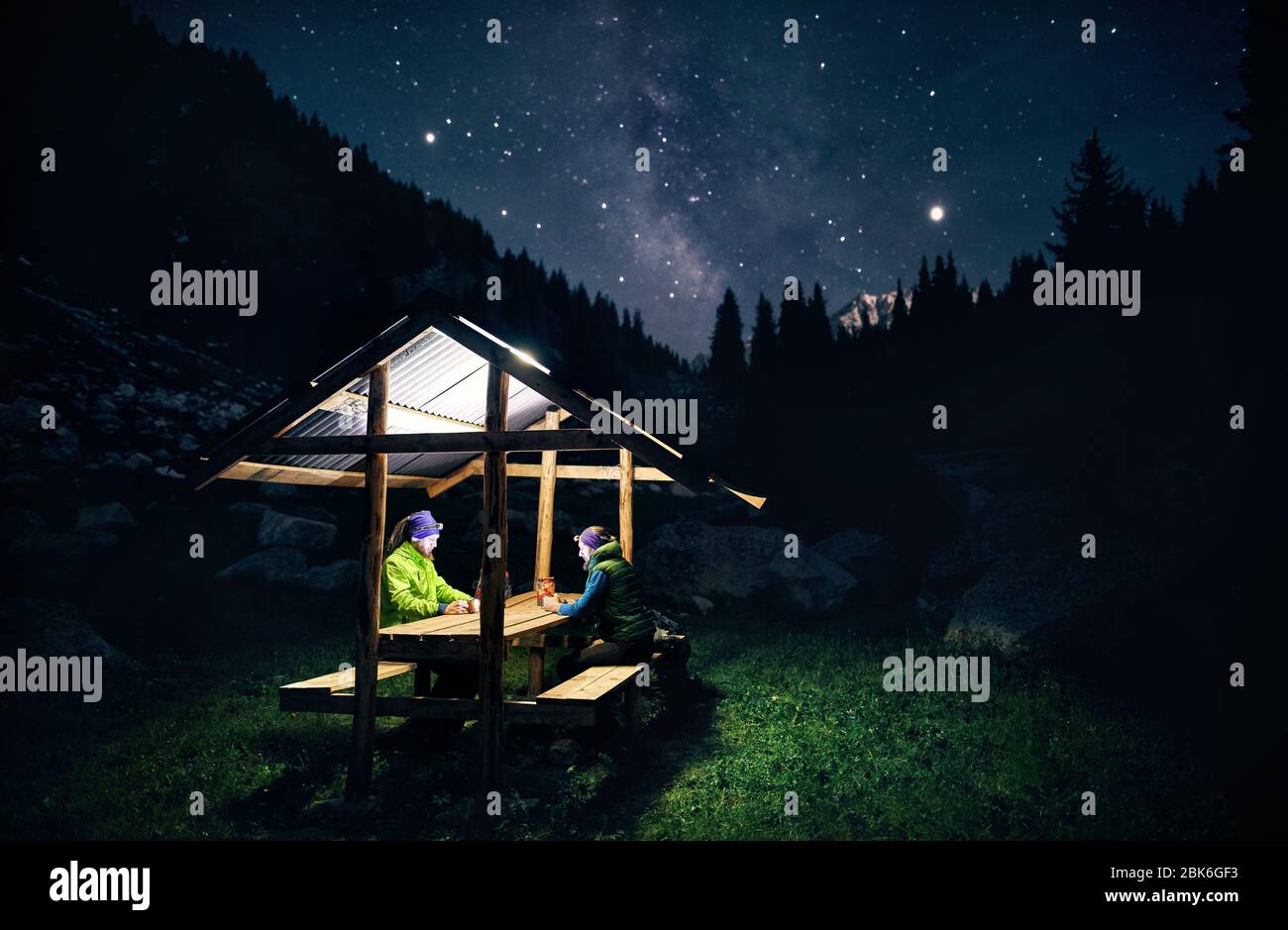 Due uomini è seduto a casa estiva in montagna a cielo notturno con stelle e lattiginosa Foto Stock