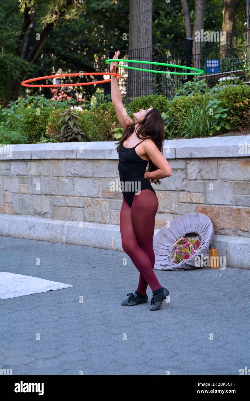 Un busker di Street artist che balla mentre gira hula cerchi. A Union Square Park a Manhattan. Foto Stock