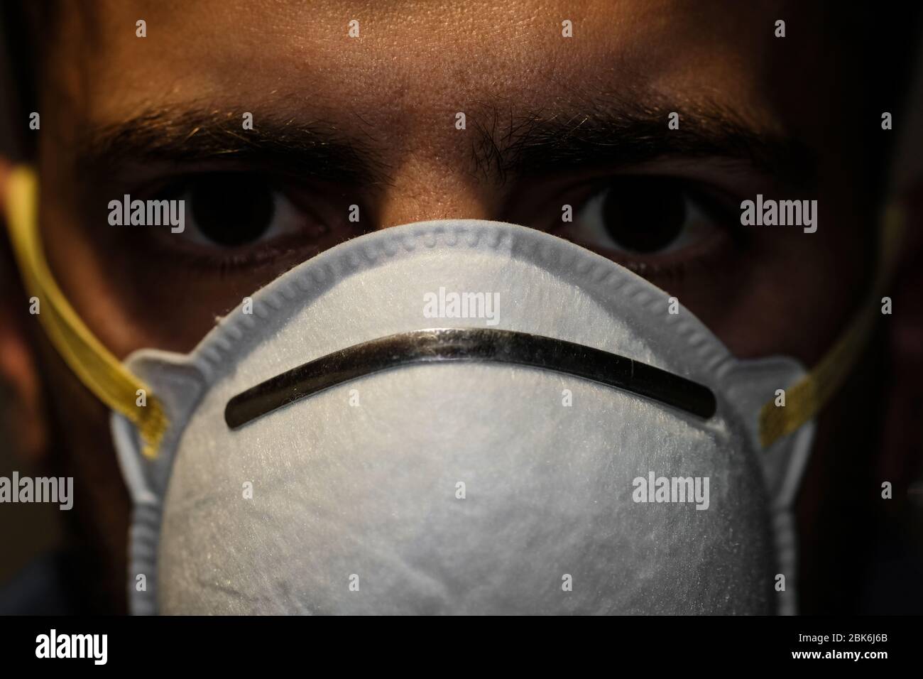 Guy faccia closeup mentre vestendo il virus della corona covid-19 maschera protettiva, malattia Foto Stock