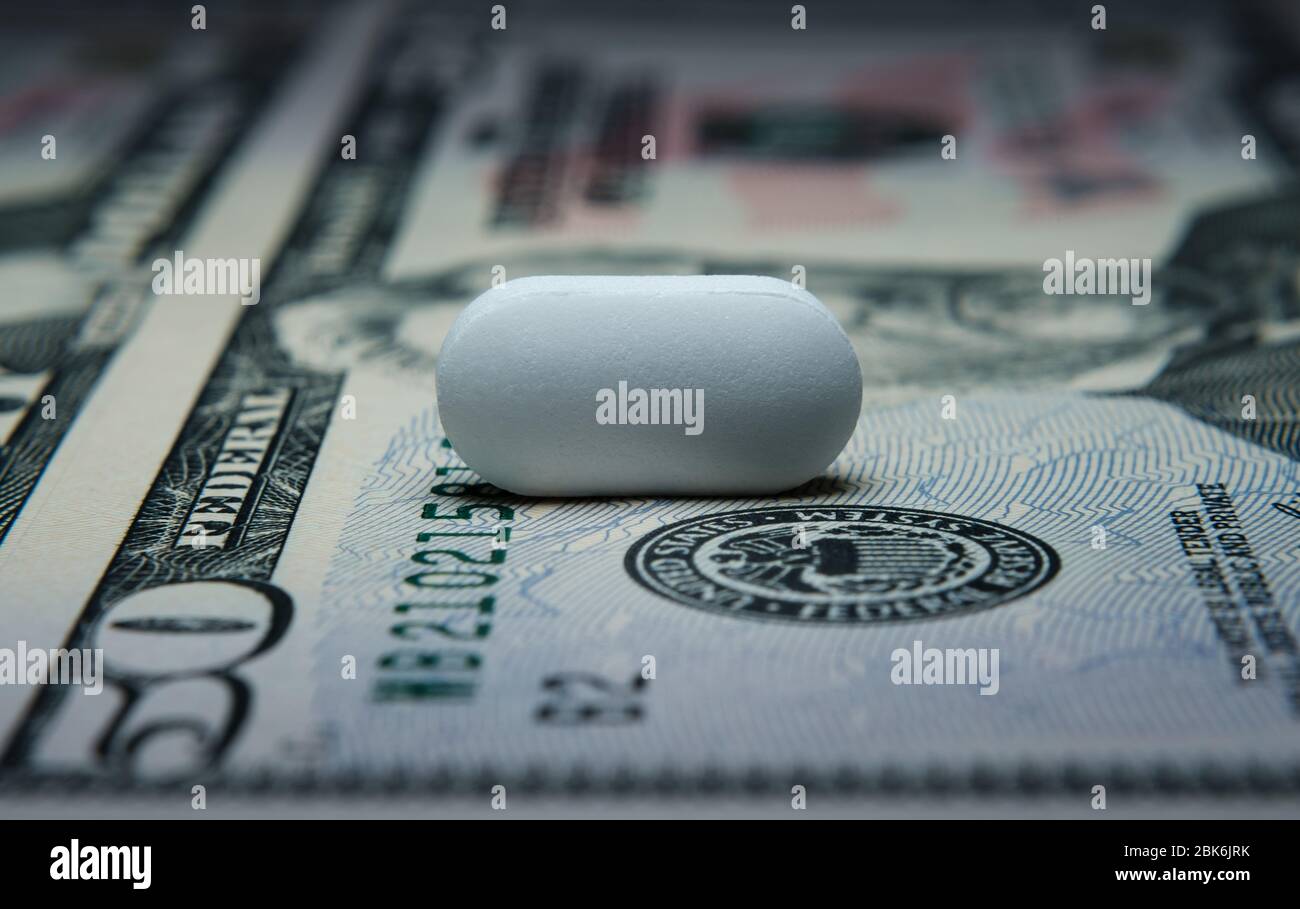 Pillola in cima a banconota da 50 dollari. Illustrativa per profitto dall'industria farmaceutica, costo delle pillole e cura medica. Foto di concetto. Foto Stock