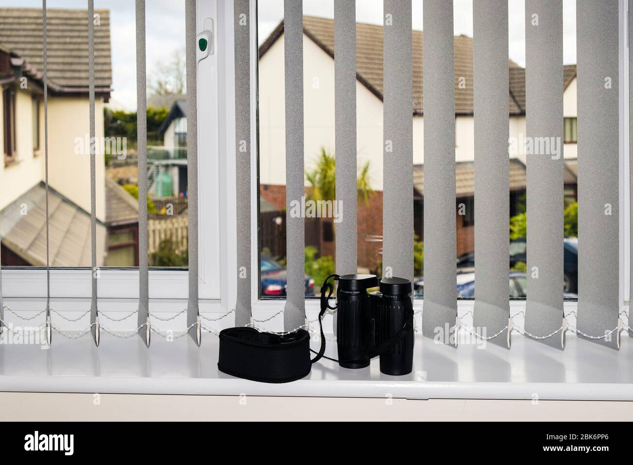 Binocoli su una davanzale per guardare attraverso una finestra per spiare e riferire sui vicini che rompono il nuovo blocco di coronavirus covid 19 soggiorno regole di casa Regno Unito Foto Stock