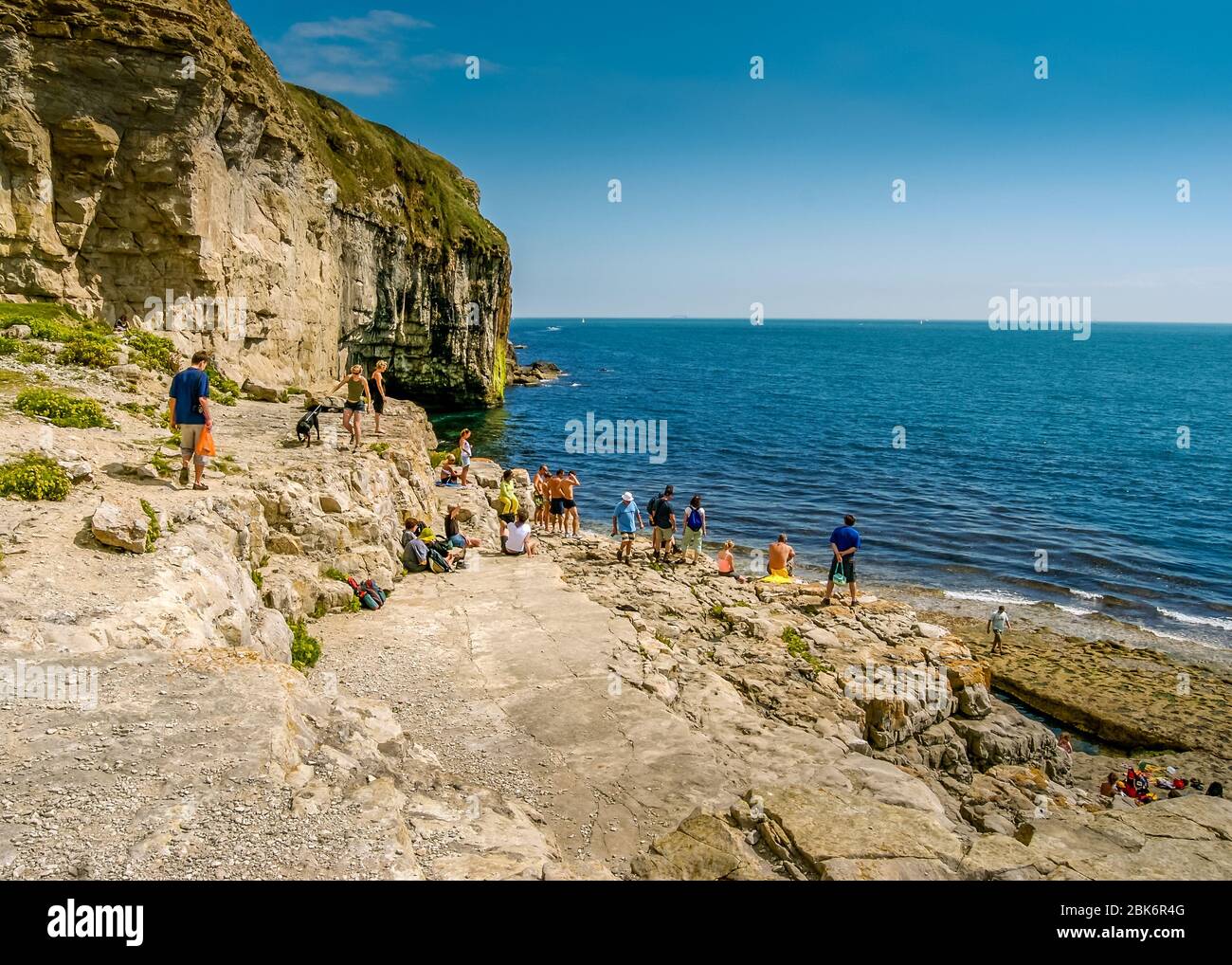 I turisti guardano al mare dalla sporgenza rocciosa di Dancing, Langton Matravers, vicino Swanage, Dorset, Regno Unito in un pomeriggio estivo soleggiato Foto Stock