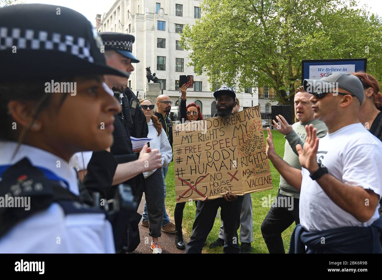 Gli agenti di polizia parlano a persone che protestano contro il blocco di Covid-19 al di fuori del New Scotland Yard a Londra. Foto Stock
