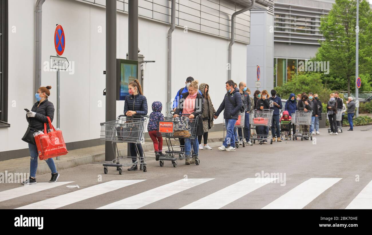 Persone che si accodano fuori da un supermercato a Monaco, Baviera, Germania Foto Stock